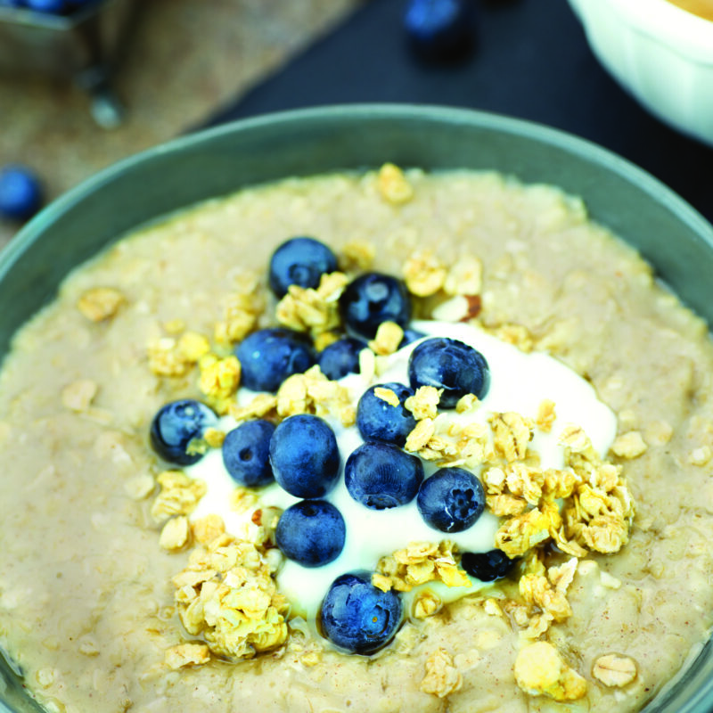 A bowl of honey yogurt oatmeal topped with a sprinkle of oats and fresh blueberries for a delicious breakfast.