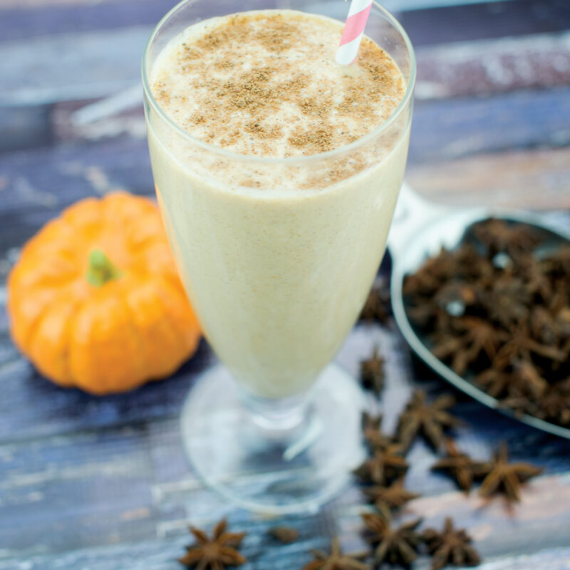 Pumpkin spice smoothie with fall decorations in the background.