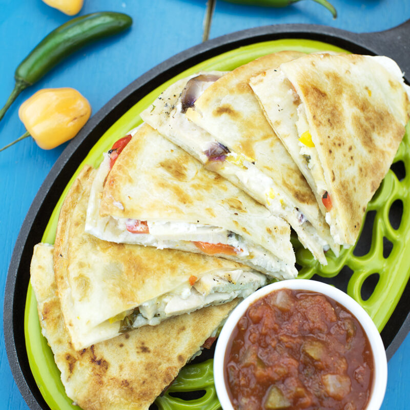 A southwest chicken fajita quesadilla filled with seasoned chicken, bell peppers, and onions, served with salsa and sour cream on the side.