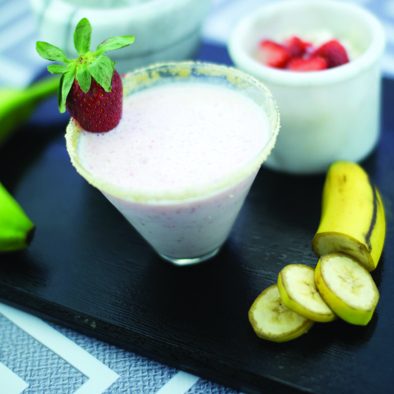 A refreshing strawberry banana yogurt shake in a glass, garnished with a slice of strawberry and banana.