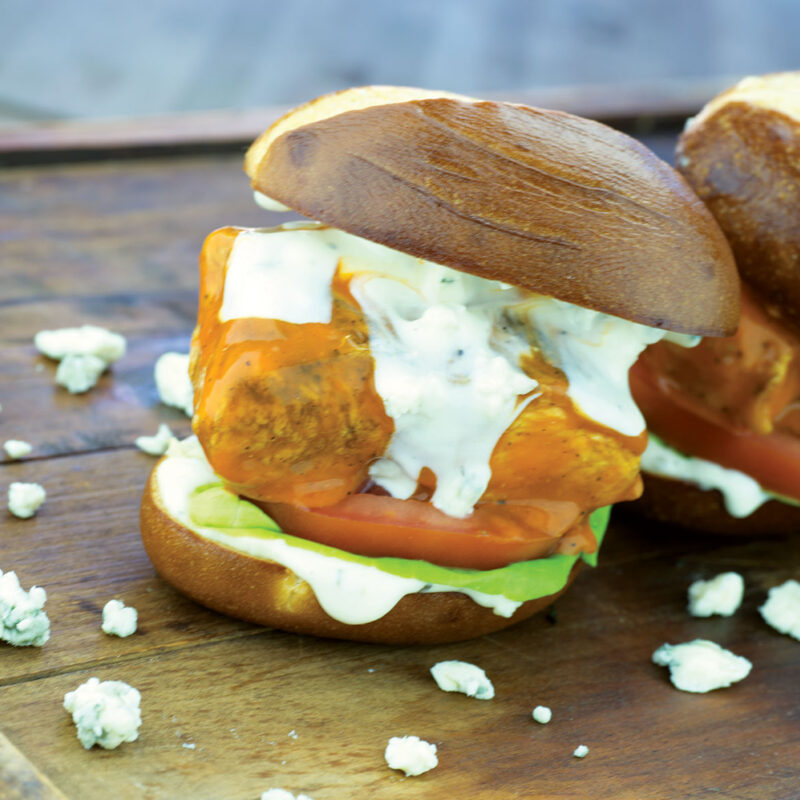 Buffalo chicken sliders topped with blue cheese crumbles on a plate.