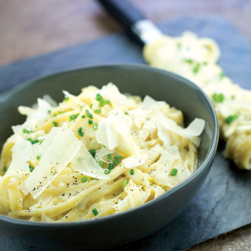 Fettuccine Alfredo topped with shaved Parmesan cheese.