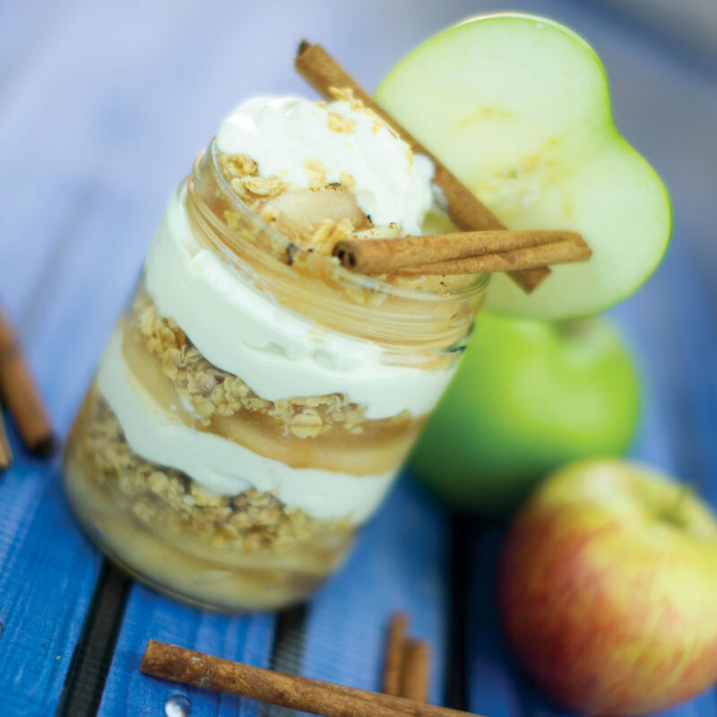 Layers of Grandma's apple pie served in a glass cup, with apple filling and pie crust.