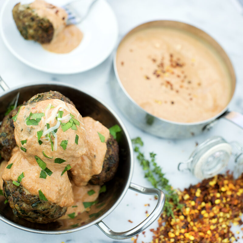 Mama Mia meatballs served with marinara sauce and garnished with fresh herbs.