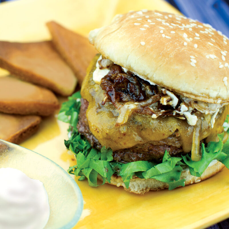 Onion Pub Burger served on a yellow plate with toppings.