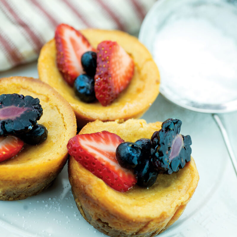 Pumpkin cheesecake cupcakes topped with fresh berries on a plate.